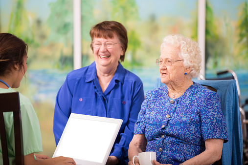 Female doctor visits elderly woman patient in nursing home. Laptop.